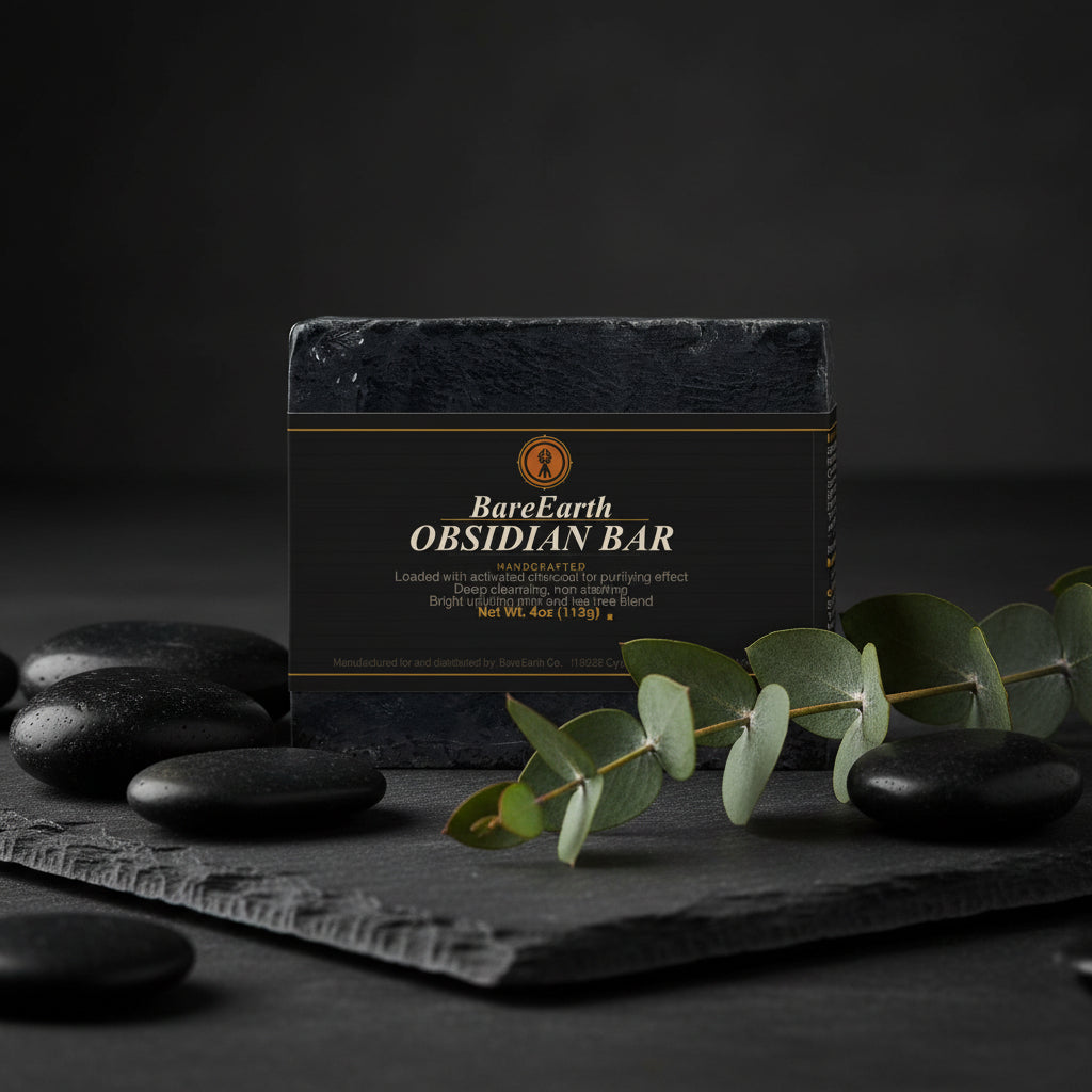 Obsidian activated charcoal soap bar on dark slate with smooth black river stones and eucalyptus sprig